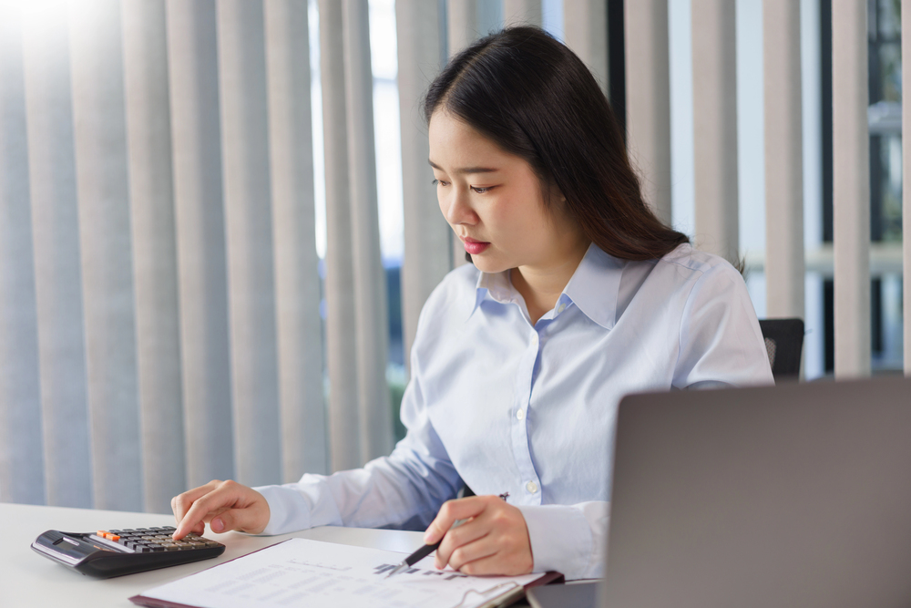 A manager at a desk working through replacement costs on a calculator